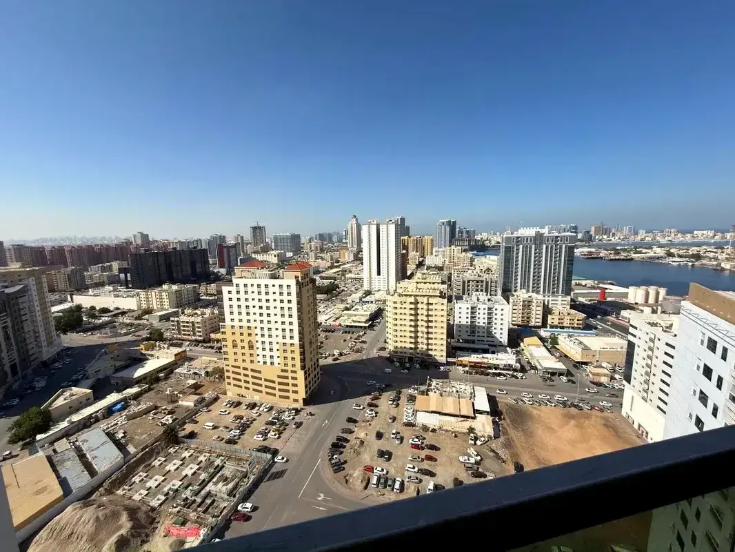 A high-angle panoramic view of Ajman's urban landscape featuring residential towers and a glimpse of the sea, listed by Casttio