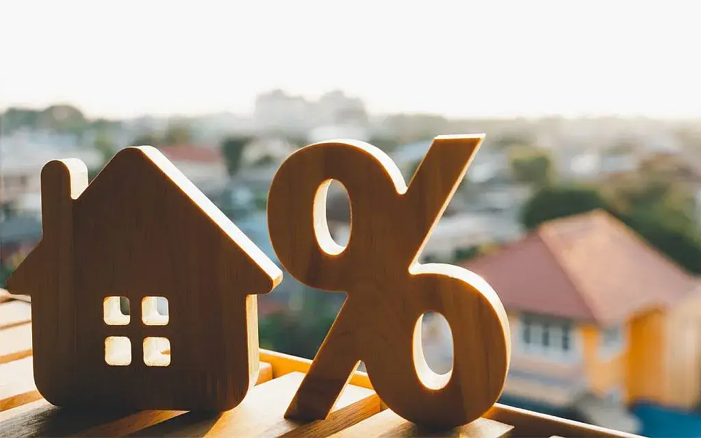 A wooden percentage symbol and a house model, symbolizing real estate tax rates in the UAE, analyzed by Casttio