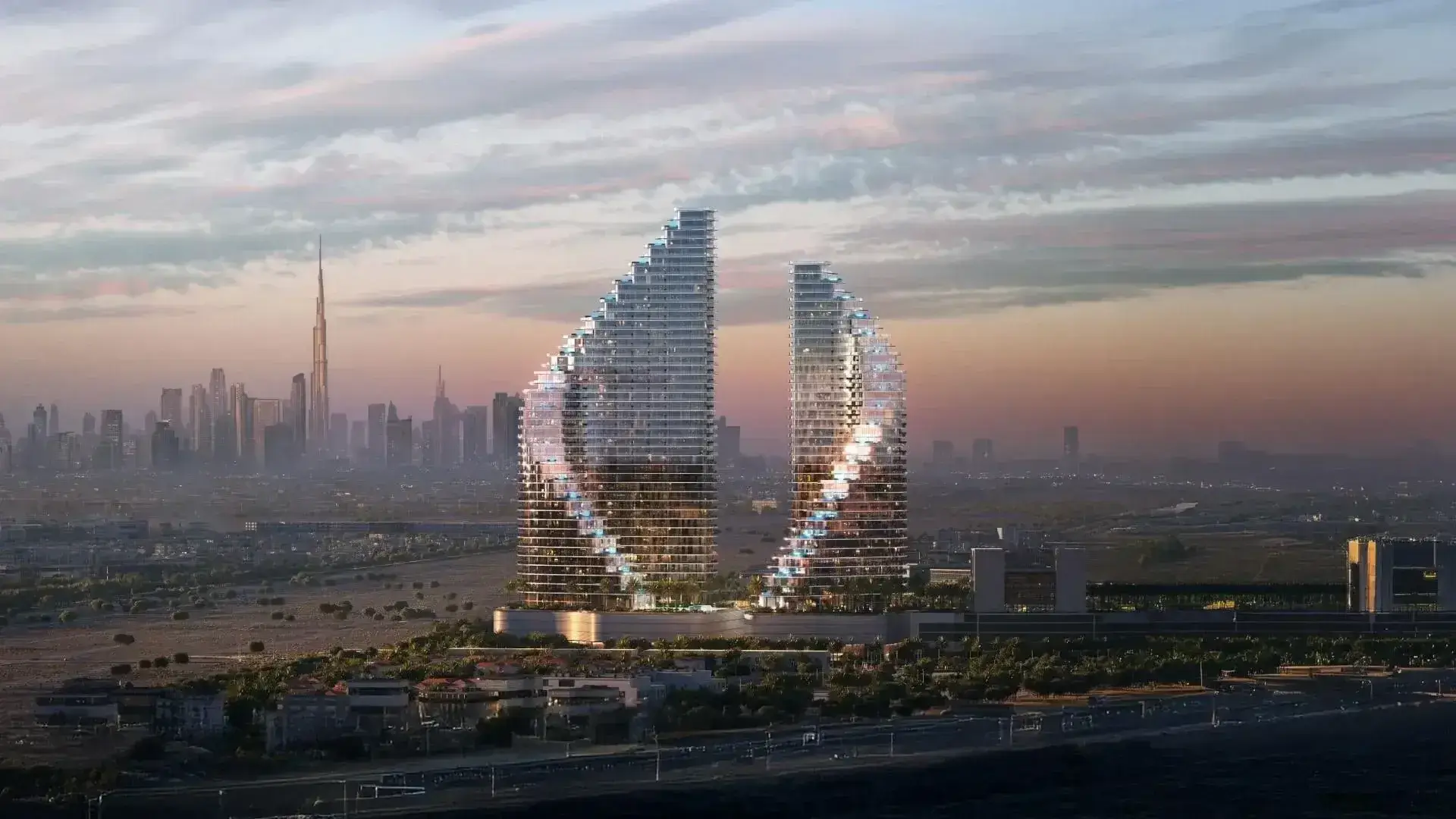 Binghatti Skyflame Majan: Panoramic sunset view of Binghatti Skyflame towers in Majan with the Downtown Dubai skyline and Burj Khalifa in the distant background.