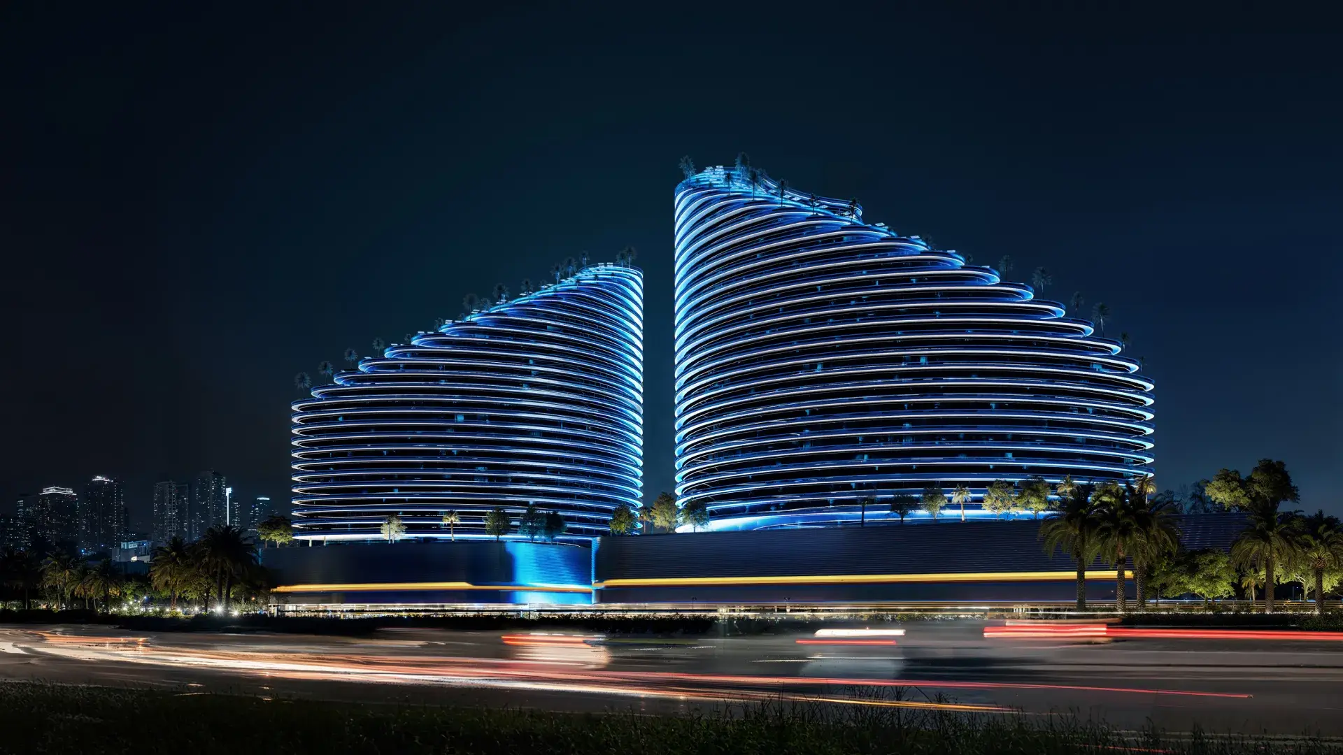 Street-level view of Binghatti Skyflame in Majan illuminated with striking blue LED lights at night, showcasing modern architectural design by Casttio.