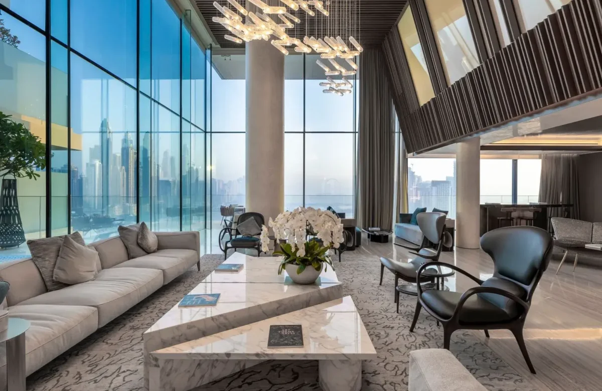 Luxury Penthouse Dubai Market: Elegant double-height living room in a Dubai luxury penthouse with floor-to-ceiling glass windows overlooking the city skyline.
