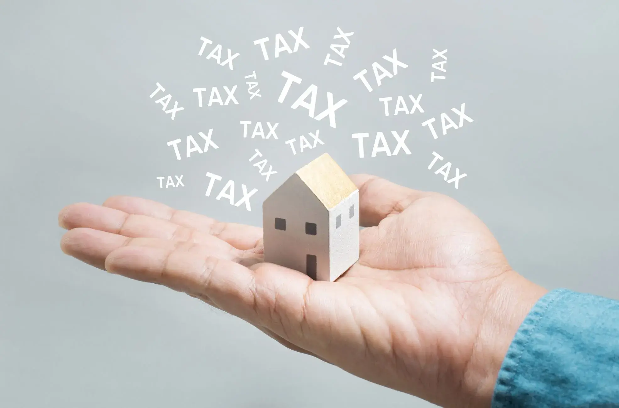 Property Tax in Dubai Guide: Hand holding a miniature house with tax symbols floating away, symbolizing Dubai's zero property tax policies for investors.